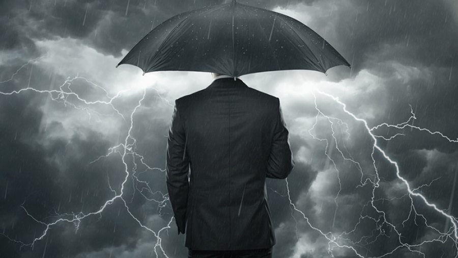 Business man under umbrella in storm