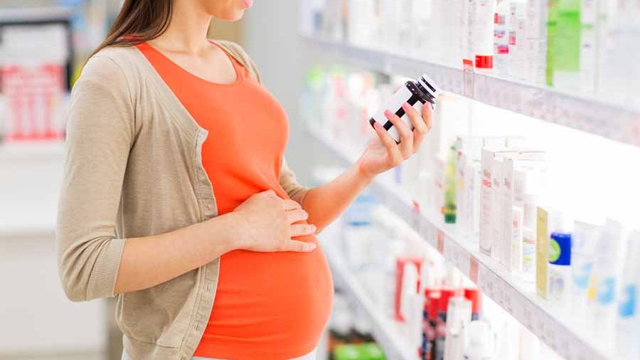 Pregnant woman reading prescription bottle