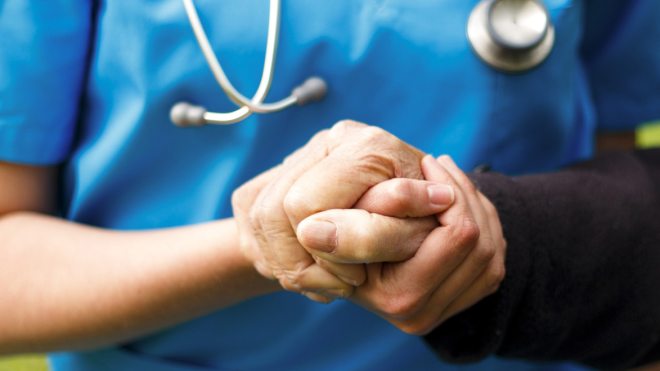 Nurse holding elderly patient's hand 
