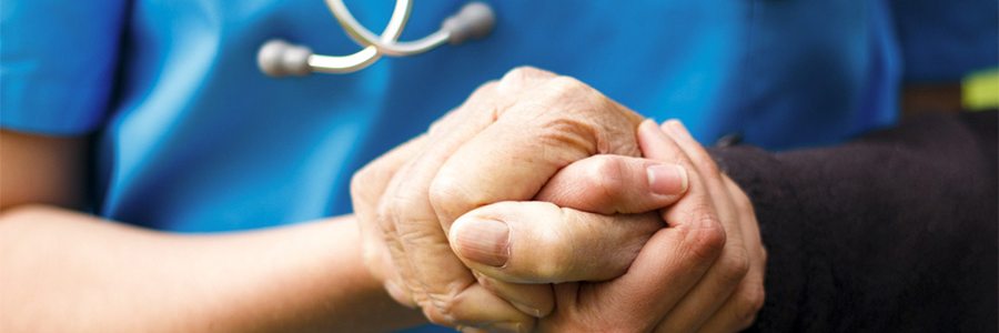 Nurse holding elderly patient's hand 